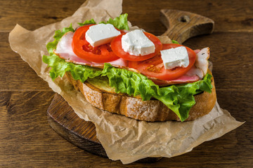 Delicious sandwich and lager beer on wooden table with dark background.