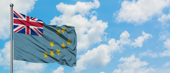 Tuvalu flag waving in the wind against white cloudy blue sky. Diplomacy concept, international relations.