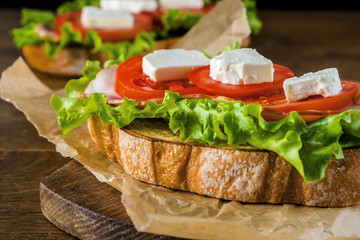 Delicious sandwich and lager beer on wooden table with dark background.