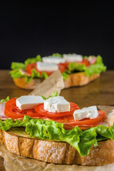 Delicious sandwich and lager beer on wooden table with dark background.