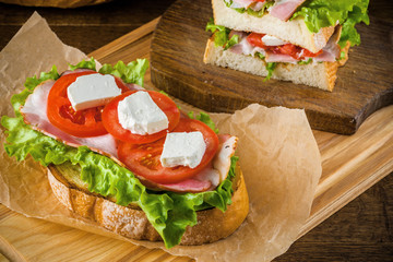 Delicious sandwich and lager beer on wooden table with dark background.