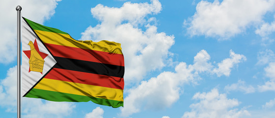 Zimbabwe flag waving in the wind against white cloudy blue sky. Diplomacy concept, international relations.