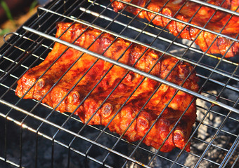Slabs smoked pork ribs grilling on barbecue grid on wooden coals. Concept background for a family summer picnic or weekend with friends. Selective focus, top view.