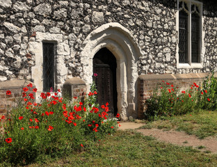 Fototapeta na wymiar Red Poppies around an English village church doorway
