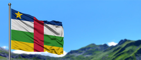 Central African Republic flag waving in the blue sky with green fields at mountain peak background. Nature theme.