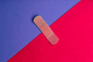 Adhesive bandage or Sticking plaster on a two colored paper background.