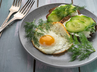 Cottage cheese sandwiches and fresh cucumber slices and scrambled eggs for a light breakfast on a turquoise plank tray.