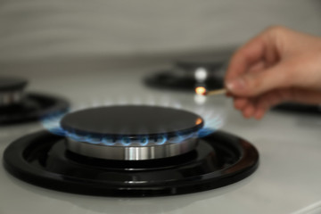 Woman lighting gas stove with match, closeup