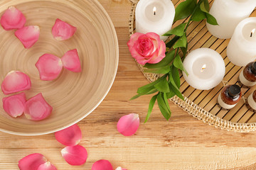 Flat lay composition with bowl of water, rose petals and candles on table. Spa treatment