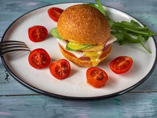 A quick lunch of hamburger and cherry tomato on a bright ceramic plate.