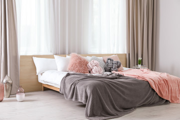 Comfortable bed with pillows and plaid in modern room interior