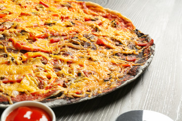 Delicious black and white pizza with sauce on wooden table, closeup