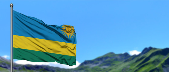 Rwanda flag waving in the blue sky with green fields at mountain peak background. Nature theme.
