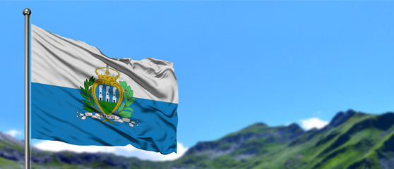 San Marino flag waving in the blue sky with green fields at mountain peak background. Nature theme.