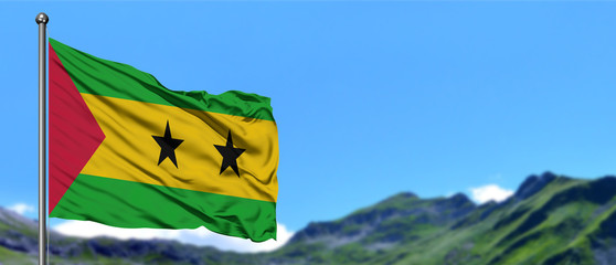 Sao Tome And Principe flag waving in the blue sky with green fields at mountain peak background. Nature theme.