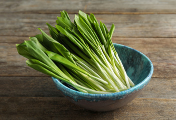 Bowl with wild garlic or ramson on wooden table