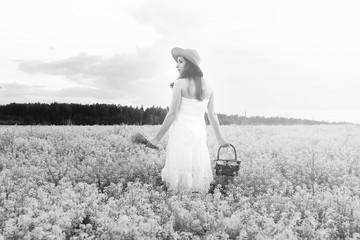 Fototapeta na wymiar monochrome portrait of young girl in a hat standing in a huge field of flowers