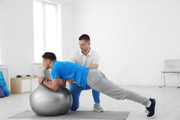 Professional physiotherapist working with male patient in rehabilitation center