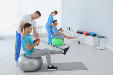Professional physiotherapists working with patients in rehabilitation center - obrazy, fototapety, plakaty