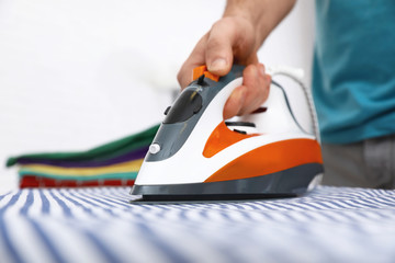 Man ironing shirt on board at home, closeup