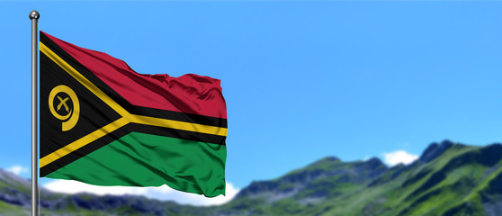 Vanuatu flag waving in the blue sky with green fields at mountain peak background. Nature theme.