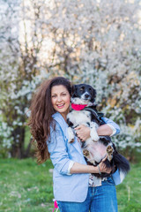 Naklejka na ściany i meble Beautiful Smiling Woman Hugging Her Cute Dog in a Spring Garden .Pet and Owner Outdoor in the Spring
