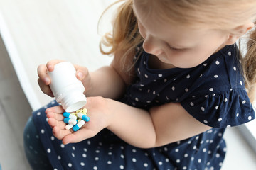 Little child with pills indoors, above view. Danger of medicament intoxication