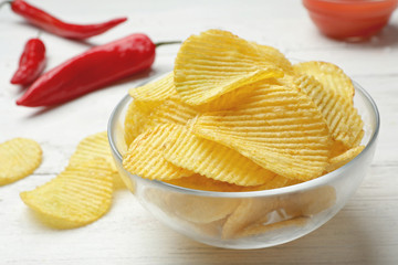 Delicious crispy potato chips in bowl on table, closeup
