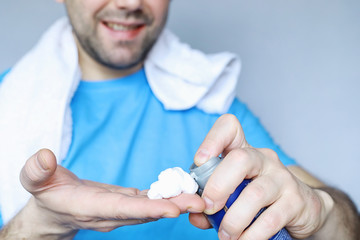 A man shaves in front a mirror. Shaving foam. Disposable razor.