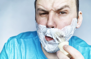 A man shaves in front a mirror. Shaving foam. Disposable razor.