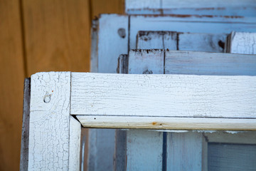dismantled old wooden windows closeup are made up in a row near the house. white window frames