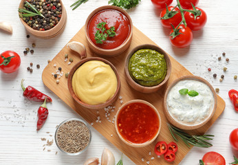 Flat lay composition with different sauces and ingredients on white wooden background