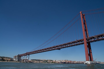 Fototapeta na wymiar Vue du fleuve sur le pont du 25 avril de Lisbonne avec un ciel bleu