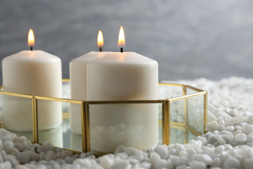 Obraz na płótnie Canvas Tray with three white burning candles on rocks