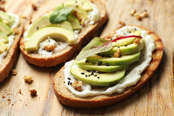 Delicious bruschettas with avocado served on wooden board, closeup
