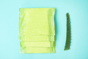 Flat lay composition with menstrual pads and aloe leaf on color background. Gynecological care