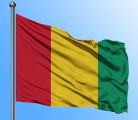 Guinea flag waving in the deep blue sky background. Isolated national flag. Macro view shot.