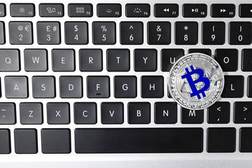 Silver bitcoin on computer keyboard, top view. Space for text