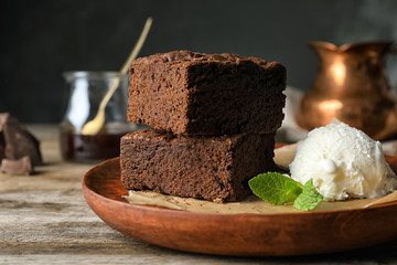 Plate with fresh brownies and ice-cream on table. Delicious chocolate pie