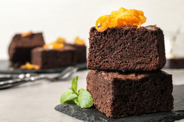 Fresh brownies decorated with orange peel and mint on table, space for text. Delicious chocolate pie