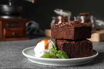 Plate with fresh brownies and ice-cream on table, space for text. Delicious chocolate pie