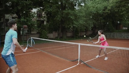Coach assisting sportswoman in playing tennis at tennis court