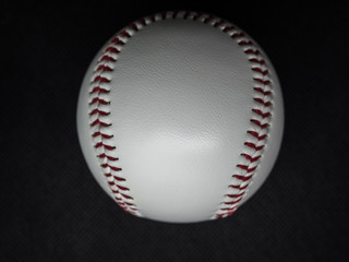 Baseball ball with red threads on a dark background
