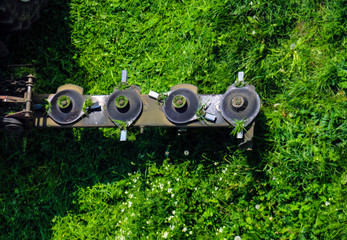 Mounted disc mower for  tractor during agricultural work, mows juicy green lawn grass during rapid rotation.