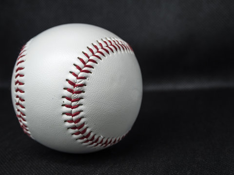 Baseball ball with red threads on a dark background