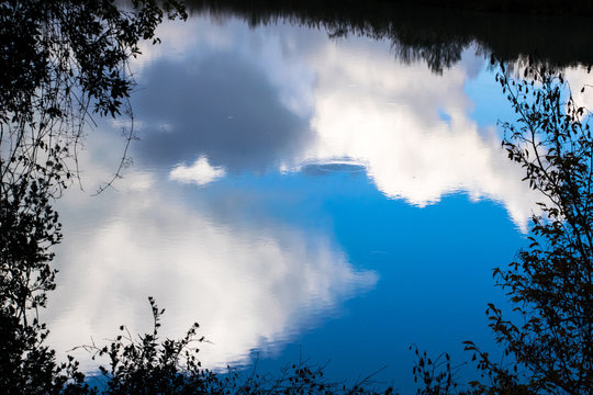 Clouds reflected in water in the Tiber river - Rome, Italy