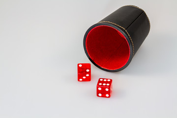 zwei Rote Würfel mit liegendem schwarzem Würfelbecher innen rot freigestellt