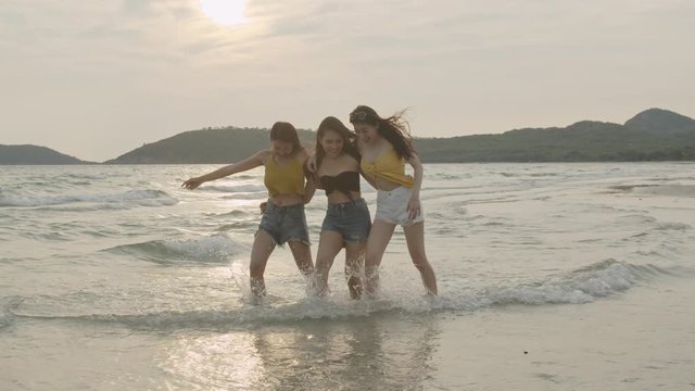 Group of Asian young women walking on beach, friends happy relax having fun playing on beach near sea when sunset in evening. Lifestyle friends travel holiday vacation summer concept. Slow motion shot