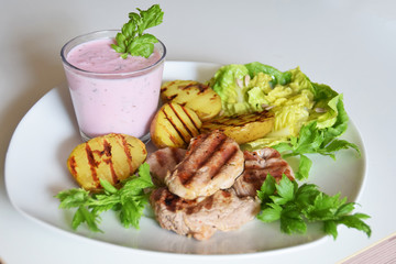 grilled potatoes and grilled pieces of sirloin with green salad and cold beetroot soup