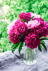 Beautiful bouquet of peonies on the window overlooking the garden - a cozy home still life. Natural beauty concept